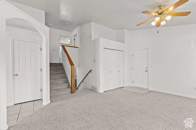 1099 Three Point Avenue Logan, UT 84321 - Photo 4 of 27 Tiled spare room featuring carpet floors, a ceiling fan, arched walkways, and stairs