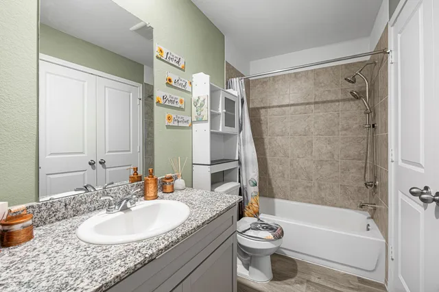 a bathroom with a granite countertop sink toilet and shower