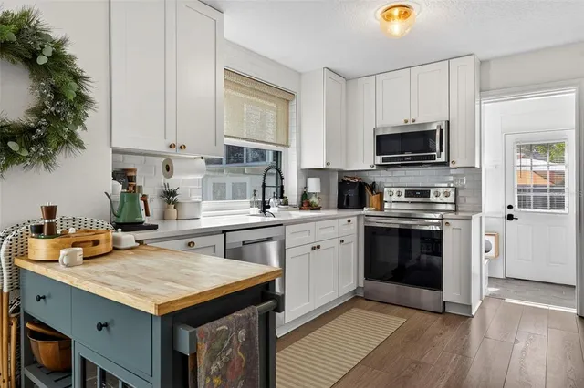 a kitchen with granite countertop a stove top oven a sink dishwasher and microwave with wooden floor