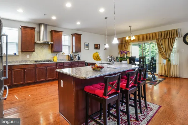 a dining room with stainless steel appliances kitchen island granite countertop a table chairs and a refrigerator