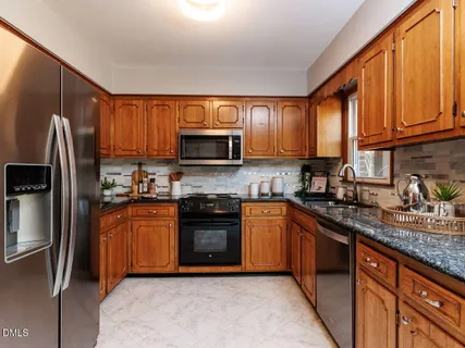 a kitchen with stainless steel appliances granite countertop a refrigerator stove top oven a sink and dishwasher