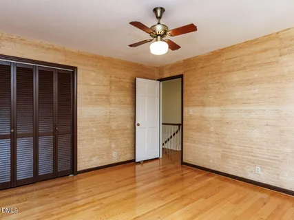 a view of empty room with wooden floor and fan