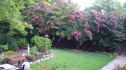 a front view of a house with a flower garden and wooden fence
