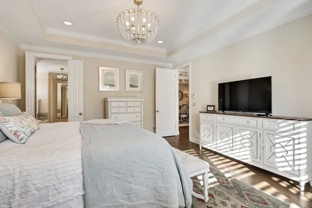 a bedroom with chandelier and flat screen tv