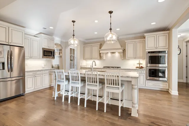 a kitchen with stainless steel appliances kitchen island granite countertop a stove a refrigerator a oven a sink with a dining table and chairs