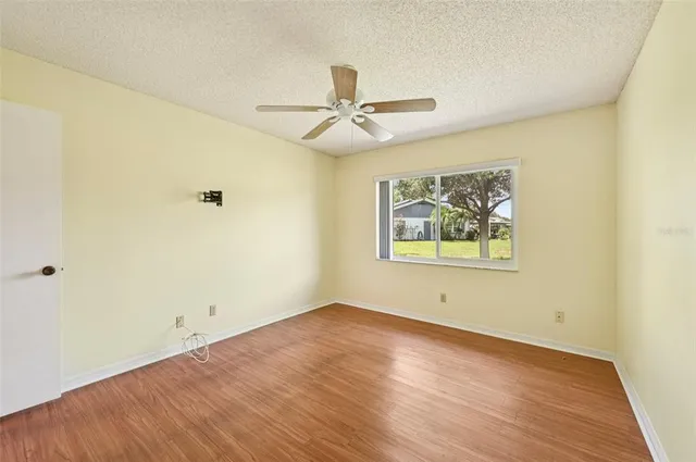an empty room with wooden floor ceiling fan and windows