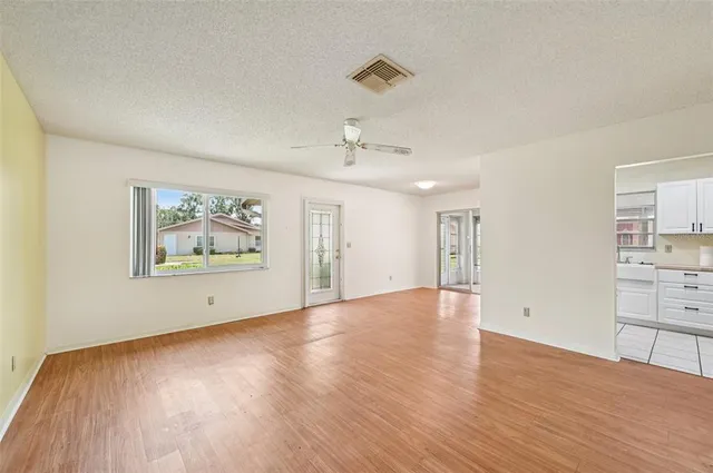 an empty room with wooden floor cabinet and windows