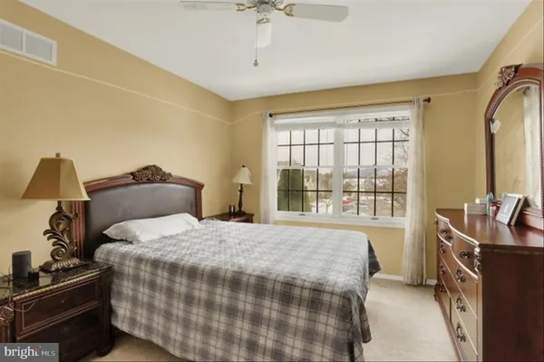 a bedroom with a bed next to a window with a flat tv screen and dresser