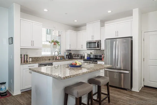 a kitchen with stainless steel appliances granite countertop a refrigerator a stove a sink a dining table and chairs