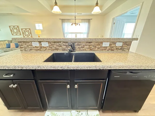 a kitchen with stainless steel appliances granite countertop a refrigerator a oven a sink a dining table and chairs with wooden floor