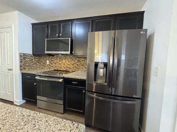 a kitchen with stainless steel appliances kitchen island a table chairs in it and wooden floors