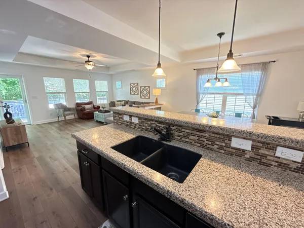 a living room with furniture kitchen view and a chandelier