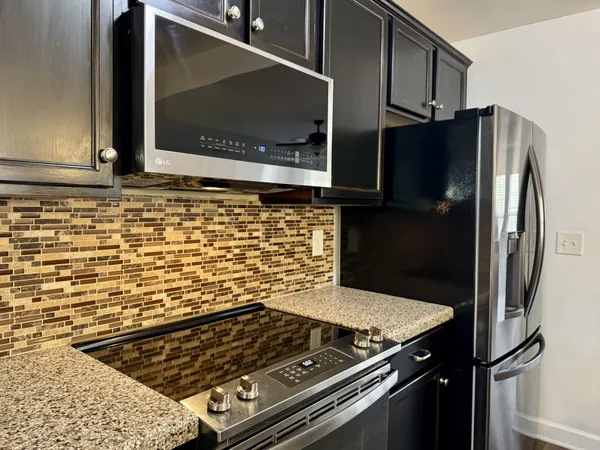 a kitchen with stainless steel appliances granite countertop a refrigerator a stove and a sink