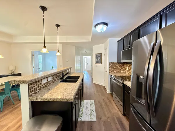 a view of a dining room and livingroom with furniture wooden floor a chandelier