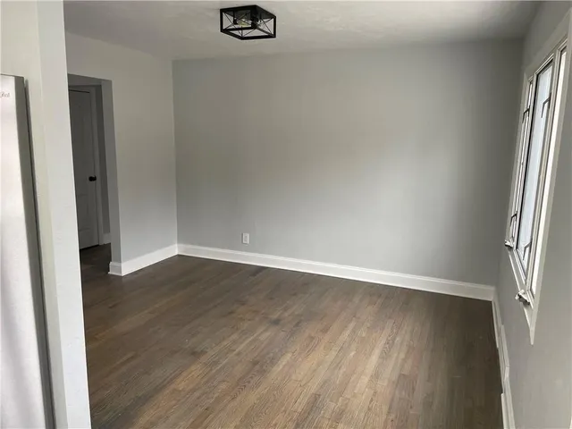 an empty room with wooden floor and window