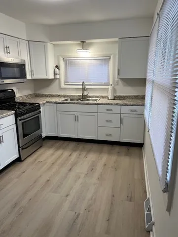 a kitchen with granite countertop white cabinets and stainless steel appliances