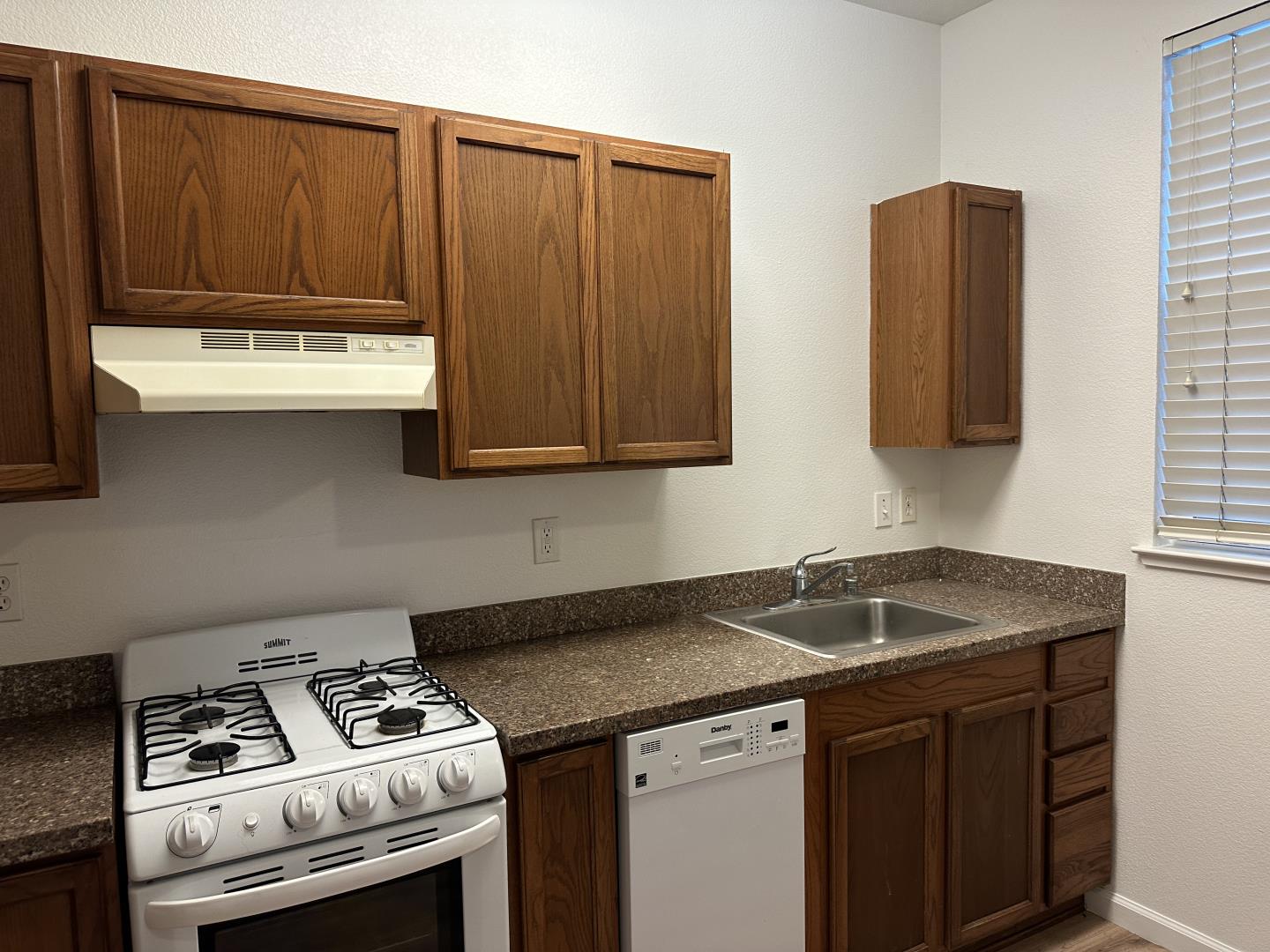 225 Pacifica Boulevard, Unit 101 Watsonville, CA 95076 - Photo 4 of 9 a kitchen with stainless steel appliances wooden cabinets and a stove top oven