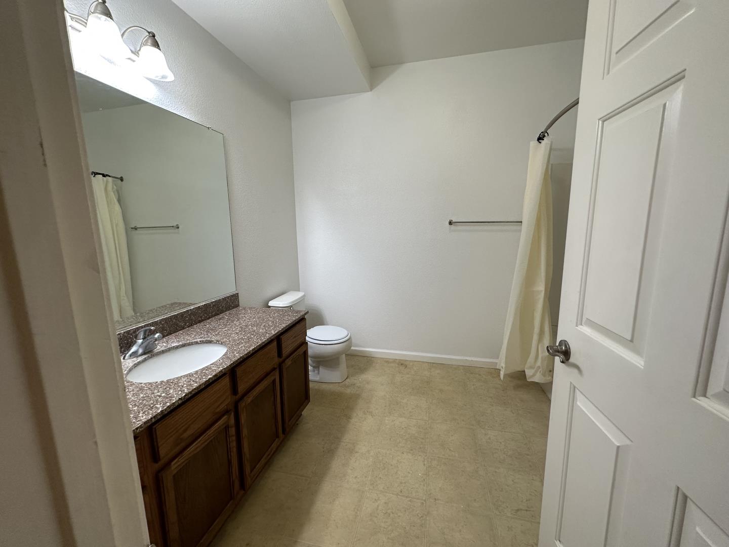 225 Pacifica Boulevard, Unit 101 Watsonville, CA 95076 - Photo 7 of 9 a bathroom with a granite countertop sink and a mirror