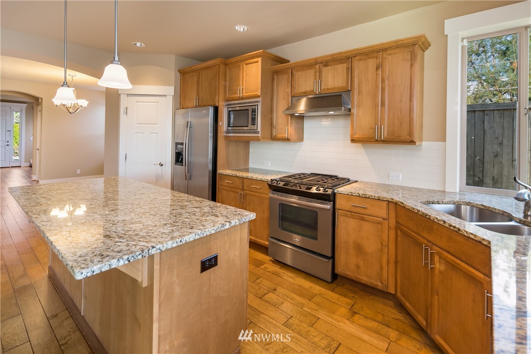 5639 Northeast 7th Place Renton, WA 98059 - Photo 13 of 23 a kitchen with stainless steel appliances granite countertop a sink a stove and a refrigerator