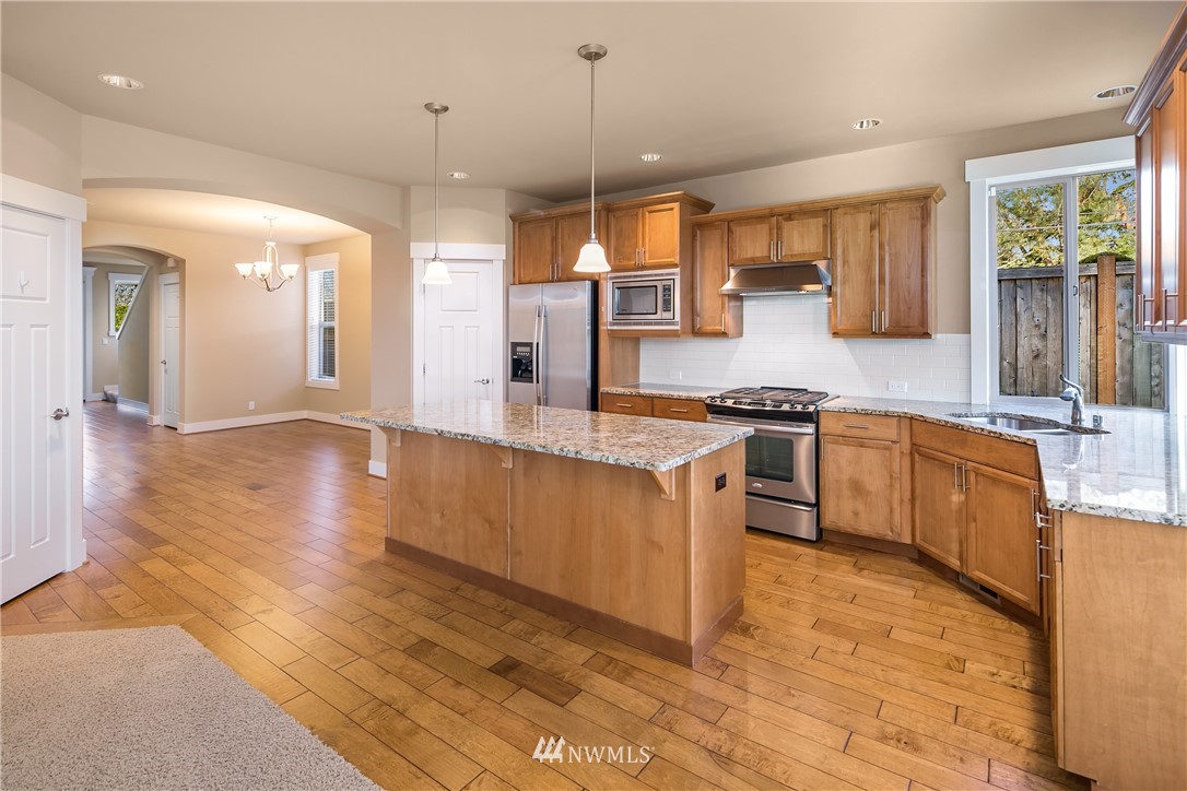 5639 Northeast 7th Place Renton, WA 98059 - Photo 8 of 23 a kitchen with stainless steel appliances granite countertop a sink a stove and a wooden floors