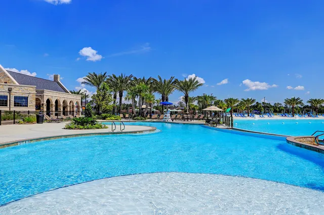 a view of a swimming pool with lawn chairs and a large tree