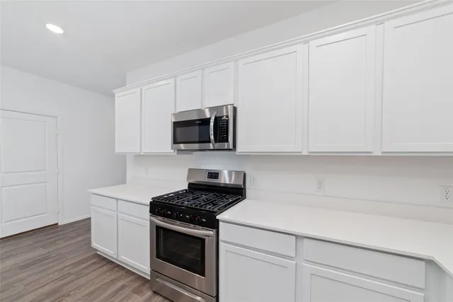 a kitchen with white cabinets and appliances