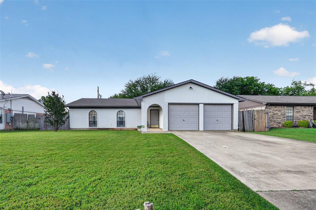 1212 Manning Road Benbrook, TX 76126 - Photo 1 of 20 White brick exterior featuring a two-car garage with gray doors, an arched entryway, and two arched windows