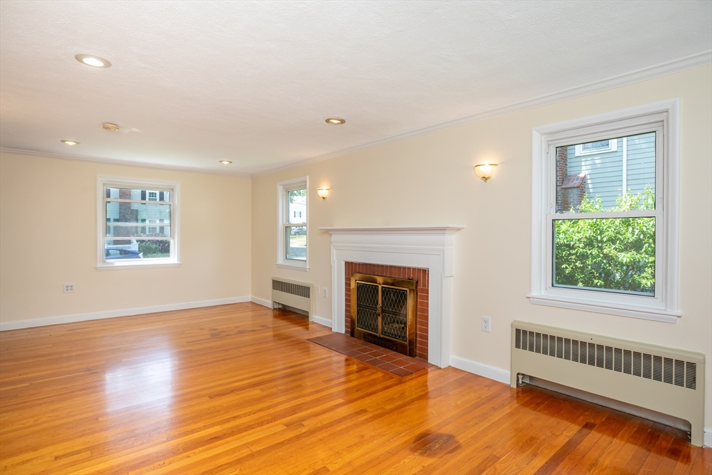 21 Allerton Road Milton, MA 02186 - Photo 6 of 42 an empty room with windows fireplace and wooden floor
