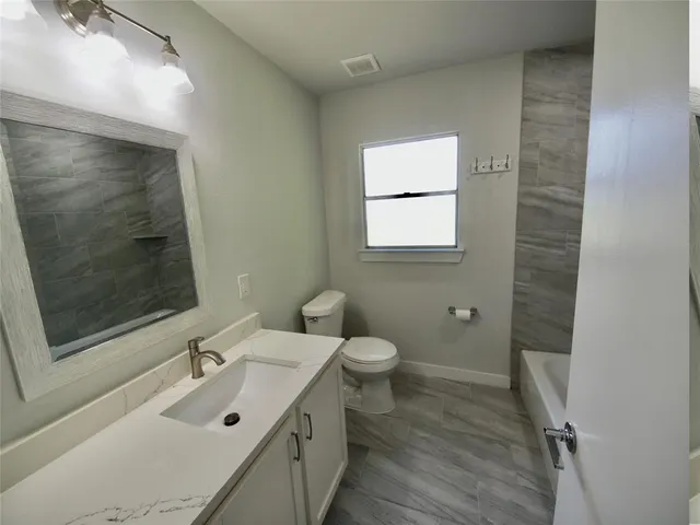 a bathroom with a sink mirror and a toilet