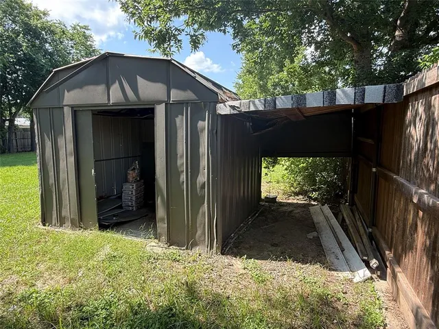a backyard of a house with wooden fence and large tree