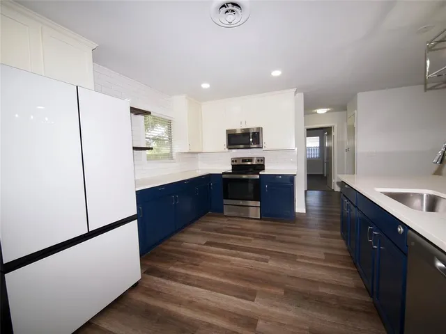 a large kitchen with wooden floor and stainless steel appliances