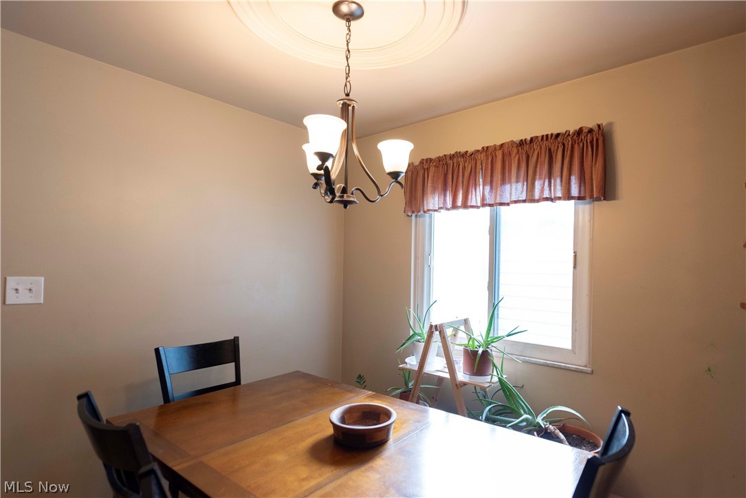 400 Baldwin Road Akron, OH 44312 - Photo 11 of 43 Dining area featuring a central chandelier with decorative ceiling medallion, neutral wall paint, and a large window