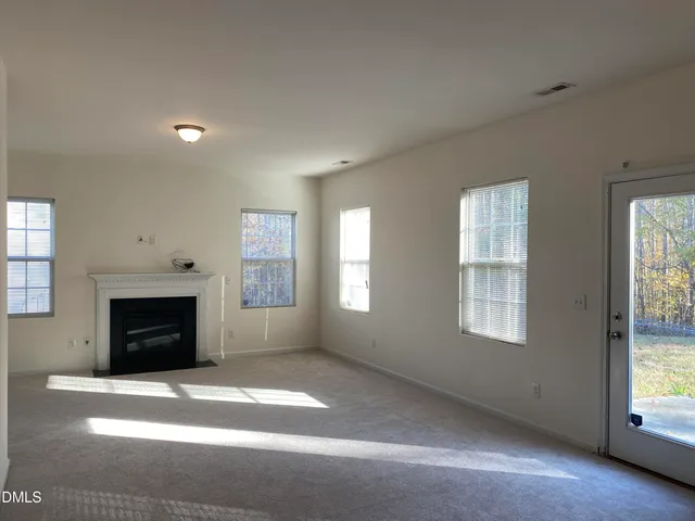 an empty room with windows and fireplace