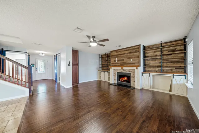 a view of an empty room with wooden floor fireplace and a window