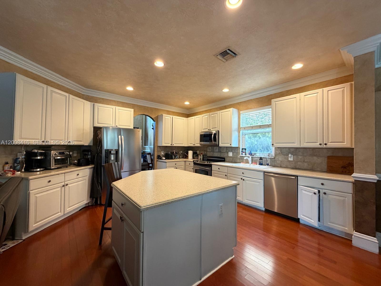 12680 Little Palm Lane Boca Raton, FL 33428 - Photo 2 of 13 a large kitchen with kitchen island a sink a stove a refrigerator and white cabinets
