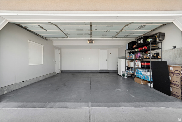 4752 South 4075th Street West Roy, UT 84067 - Photo 25 of 28 Spacious garage with light gray walls, concrete flooring, and a white window with blinds