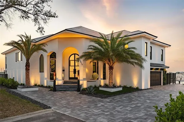 a view of a white house with large windows and potted plants