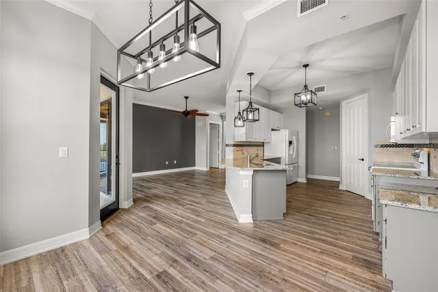 a large kitchen with stainless steel appliances kitchen island granite countertop a lot of counter space and wooden floors