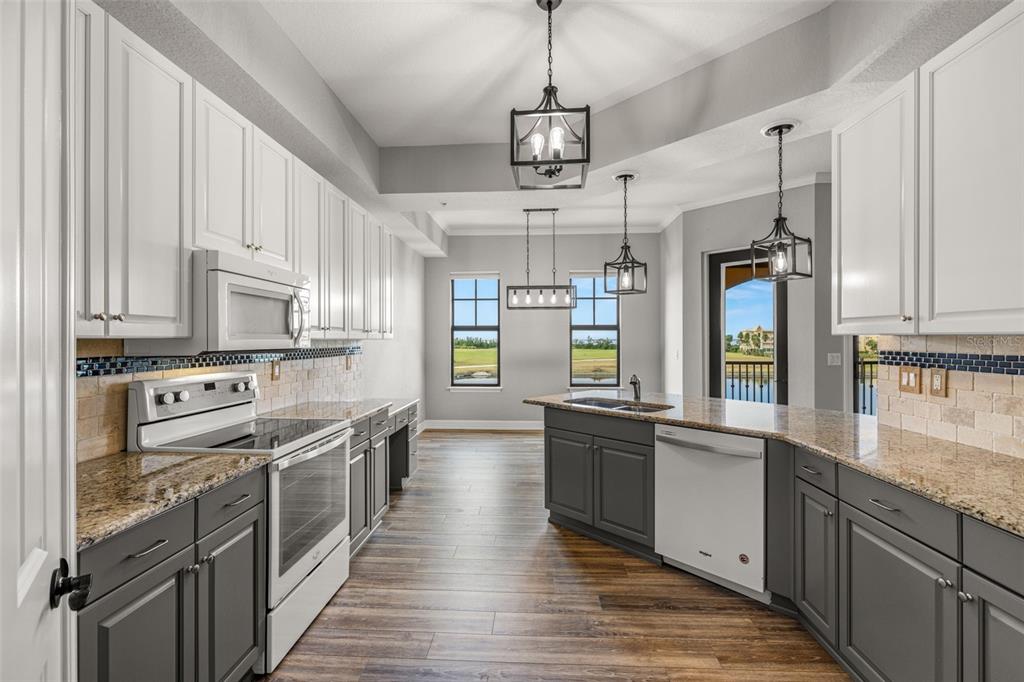 99 Vivante Boulevard, Unit 305/9935 Punta Gorda, FL 33950 - Photo 14 of 73 a large kitchen with stainless steel appliances kitchen island granite countertop a lot of counter space and wooden floors