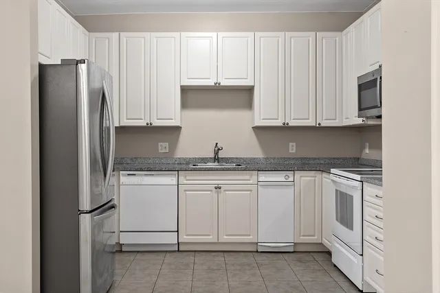 a kitchen with white cabinets and refrigerator