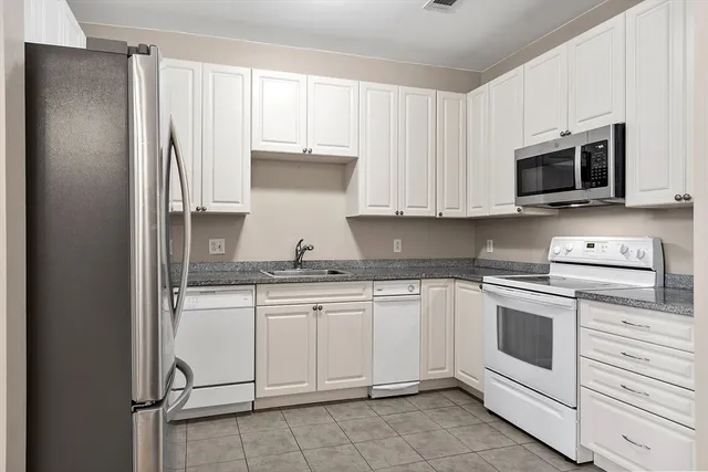 a kitchen with granite countertop white cabinets stainless steel appliances and a sink