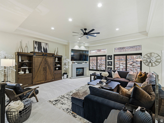 1154 Sunset Dunes Way Draper, UT 84020 - Photo 11 of 50 Living room with a ceiling fan, a tray ceiling, a glass covered fireplace, a barn door, and recessed lighting
