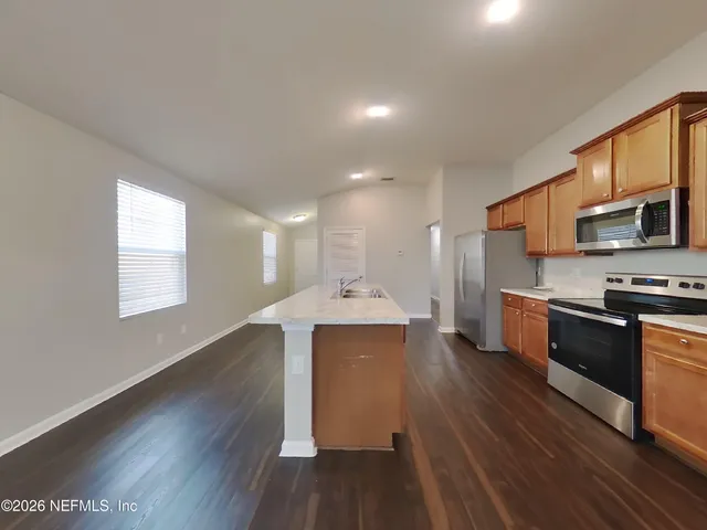 a kitchen with wooden floors and stainless steel appliances