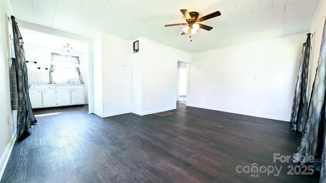 a view of a room with wooden floor and a ceiling fan