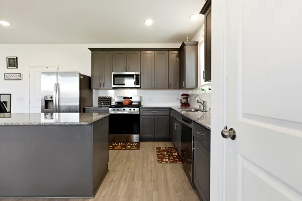 a kitchen with stainless steel appliances granite countertop a refrigerator a sink dishwasher a stove and a microwave oven on granite countertops