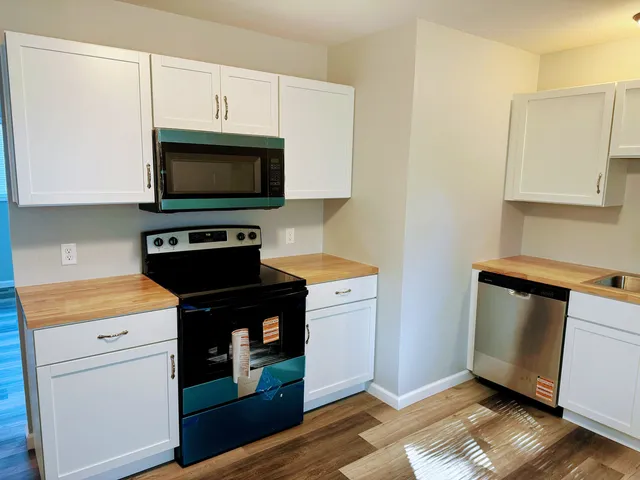 a kitchen with granite countertop a stove a microwave a sink and cabinets