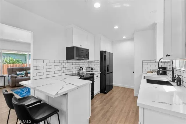 a kitchen with a refrigerator a stove a sink dishwasher with a dining table and chairs