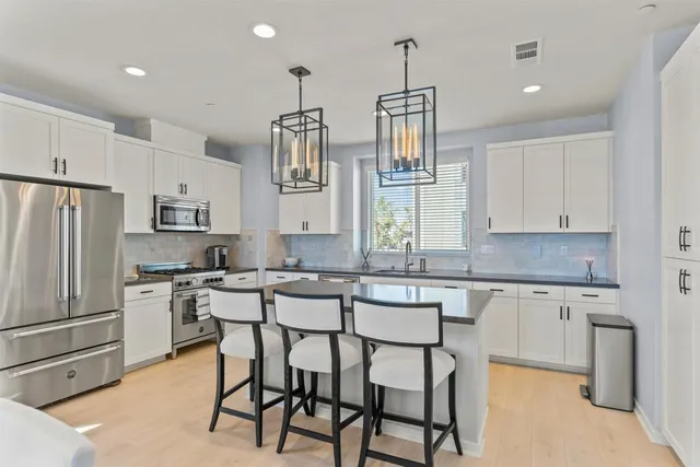 a kitchen with stainless steel appliances kitchen island granite countertop a table chairs sink and cabinets