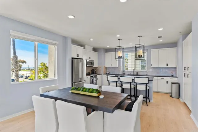 a kitchen with stainless steel appliances kitchen island granite countertop a table chairs in it and wooden floors