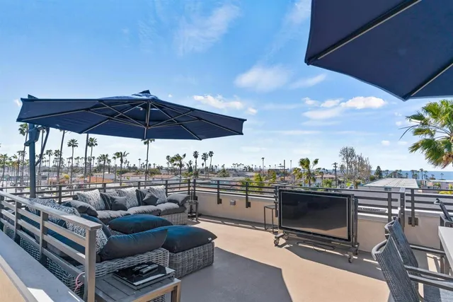 a view of a roof deck with couches under an umbrella